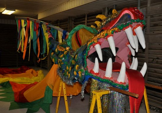 A large, multicolored Dragon head sits on yellow saw horses.