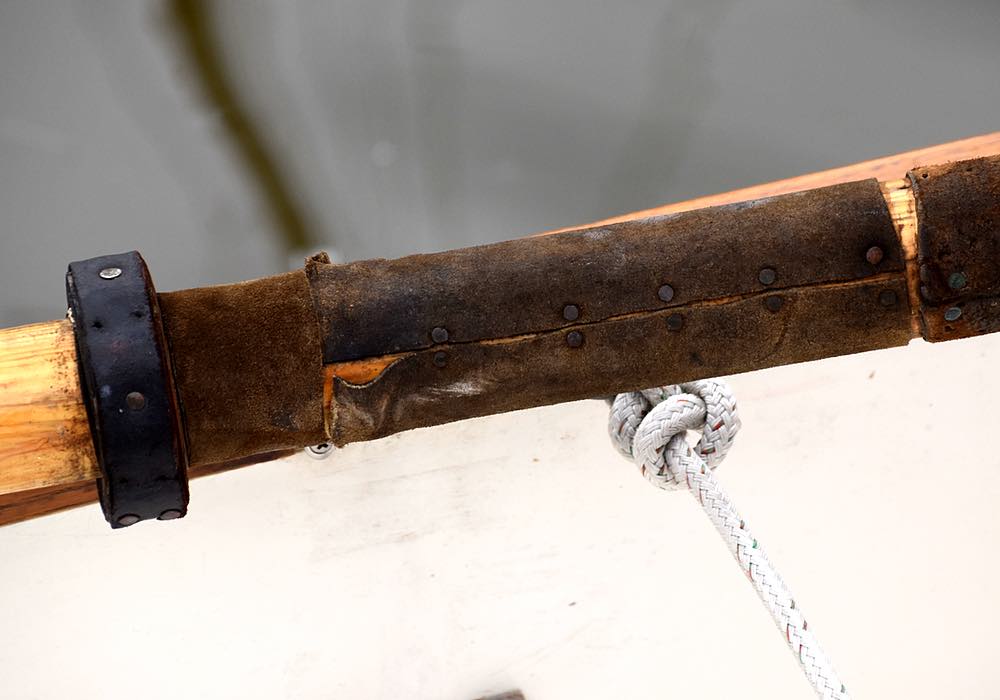 Leather wraps around the oar, rough side up, and is held in place with nails. The weather is worn from use.