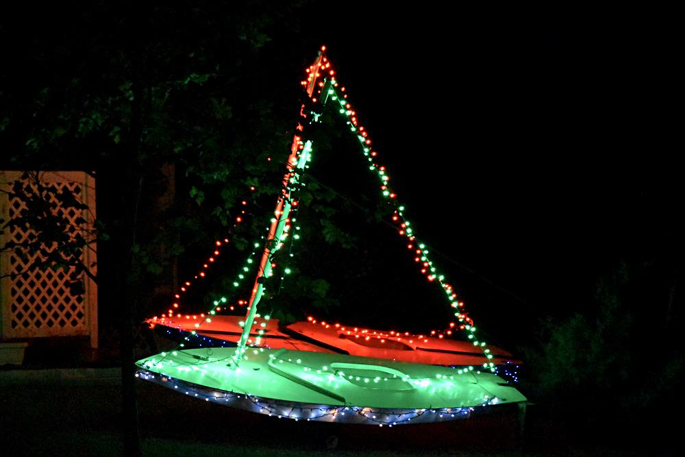 colored lights decorate two sailboats in the yard - one red and one green.'