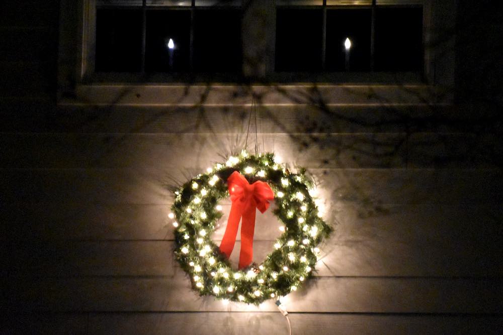 A lit wreath above the garage, and candles in the window.