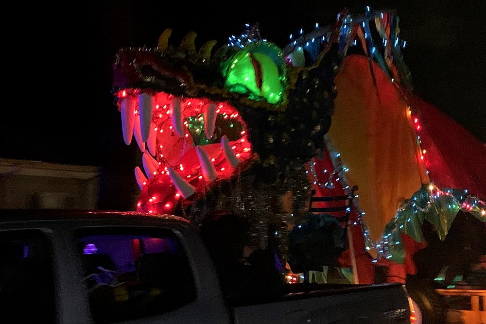 Close up of the dragon. Bright red mouth and bright green eyes shine in the darkness.