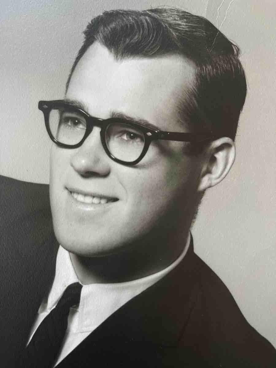 a black and white photo of a young man in black rimmed glasses